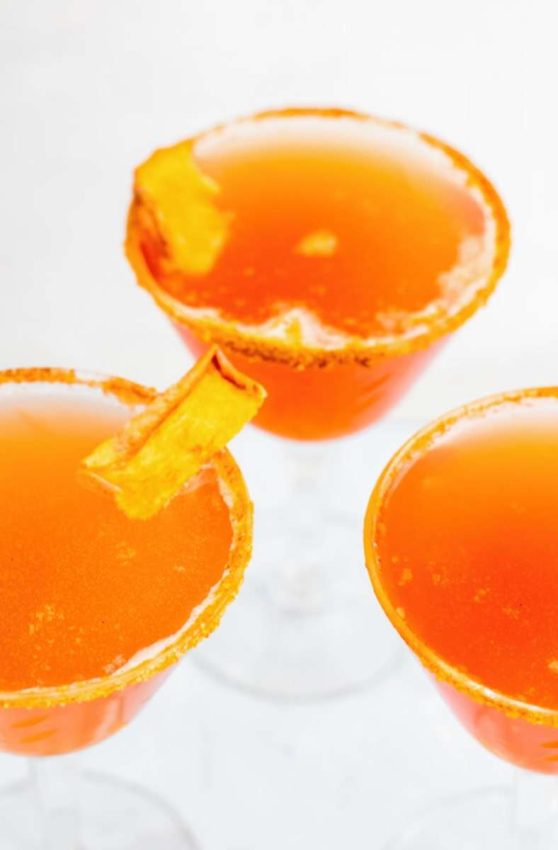 3 martini glasses rimmed with sugar and filled with a deep orange liquid