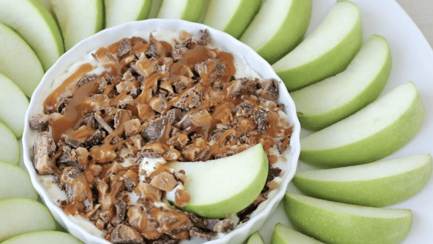 A tray of sliced apples with a ramekin of caramel cream cheese dip