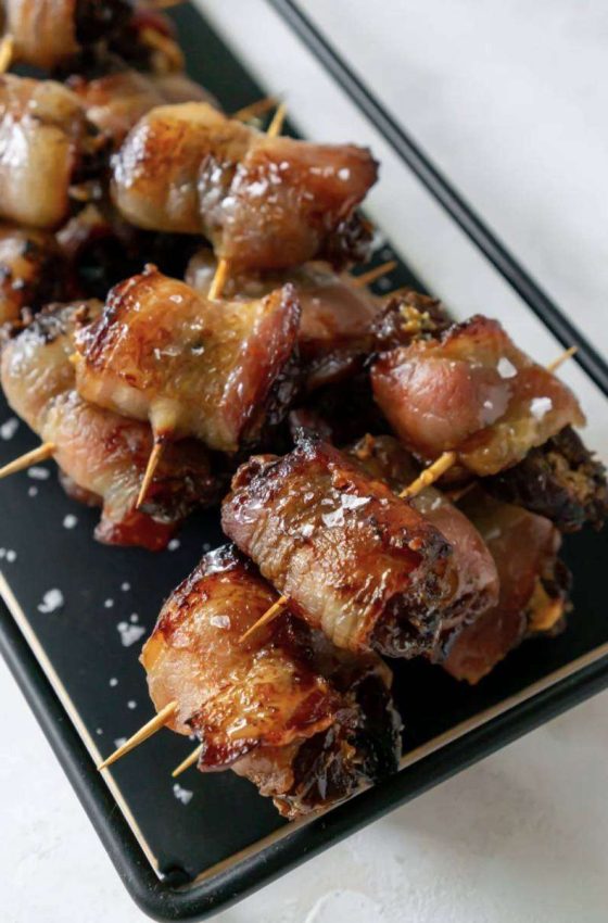A tray of dates with toothpicks holding bacon wrapped around them