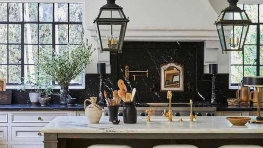 Black marble slab backsplash with aged green-black wood island and large 19th century french lanterns