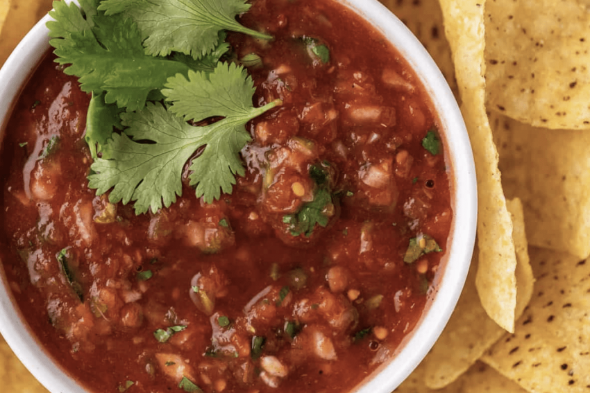 a platter of tortilla chips with a ramekin of salsa
