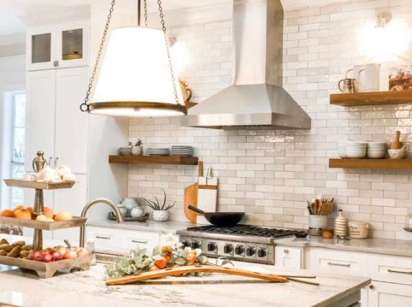 1st view of kitchen showing range, styled teak shelves, large pendant light, and fresh orange branch on the quartzite counter