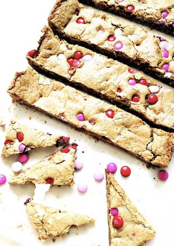 a plate of cookie bars cut into long, thin rectangles with pink & red M&Ms