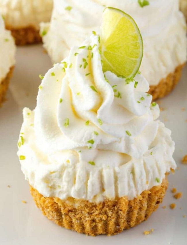 a mini key lime cheesecake with graham cracker crust and lime zest on the whipped cream