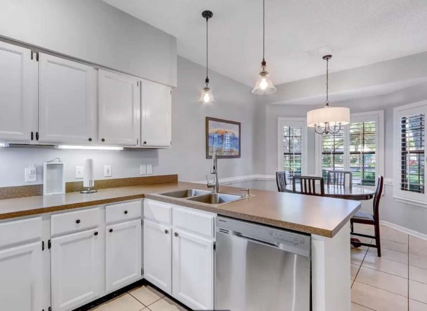 Pink beige tile floor, orange beige counters, white cabinetry and gray walls. A kitchen needing a color transformation.