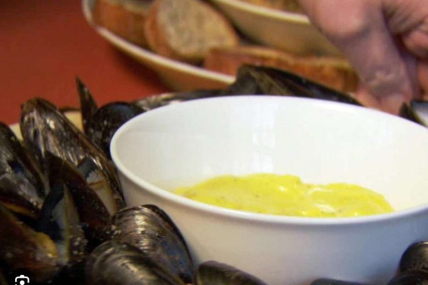 a platter of cooked mussels with a bowl of bright yellow saffron mayonnaise