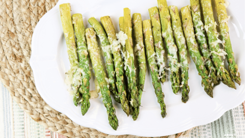 a platter of asparagus with melted parmesan on top