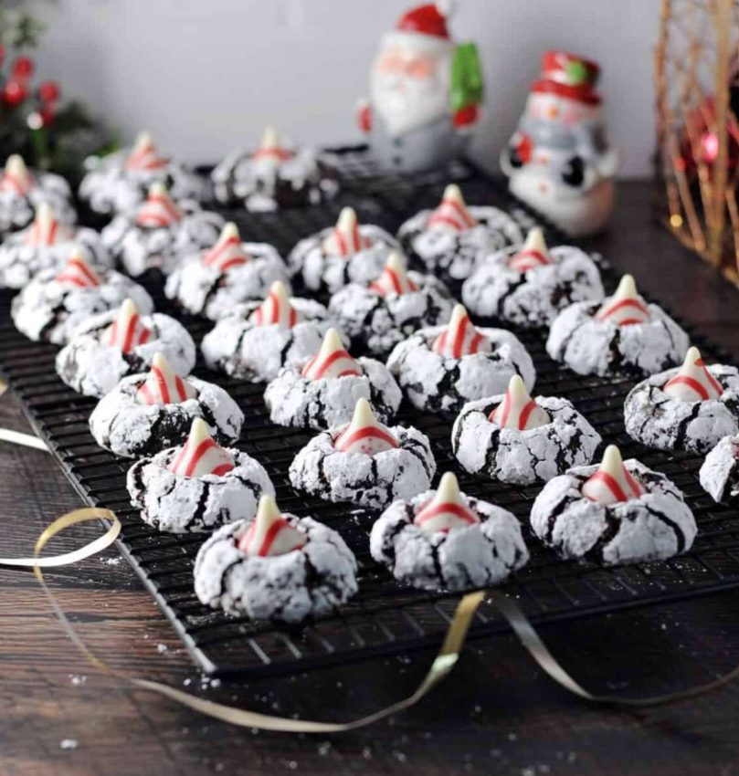 a cooling rack lined with chocolate cookies with peppermint kisses