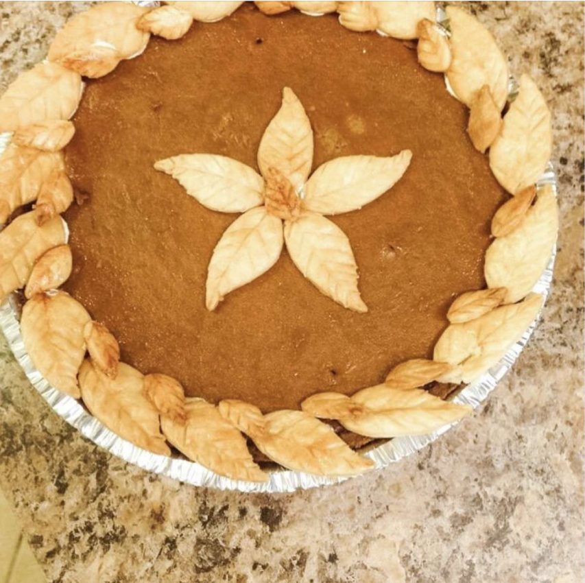 a pumpkin chai pie in a foil tin with a circle of pie-dough leaves