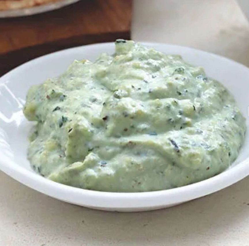 a bowl of thick, light green cheesy pesto