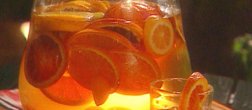 a pitcher and glass filled with white sangria and different types of orange slices