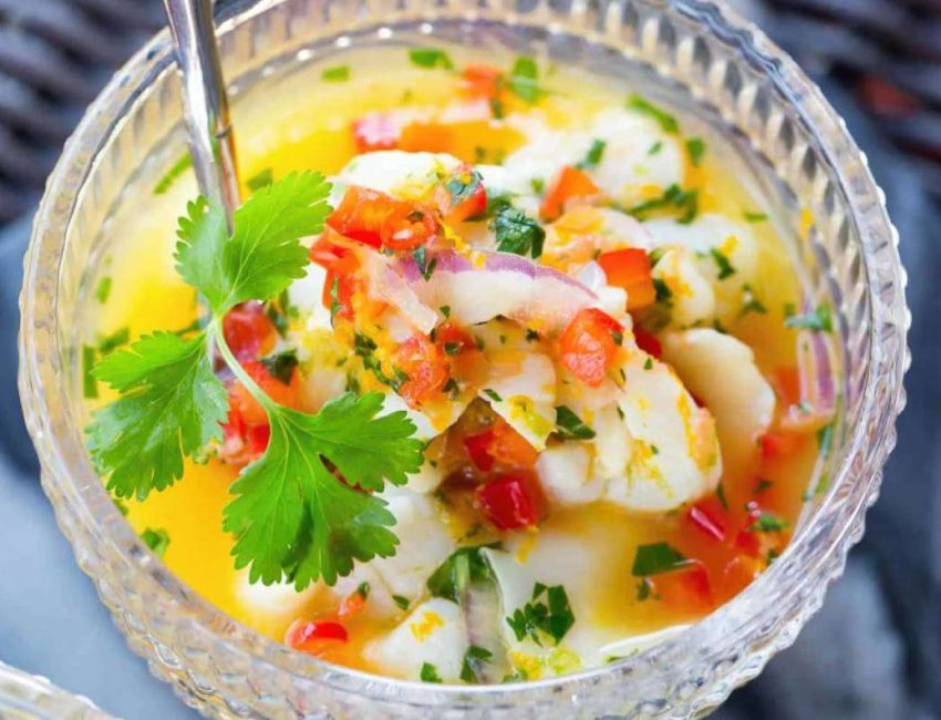 an individual bowl of scallop ceviche garnished with a sprig of parsley