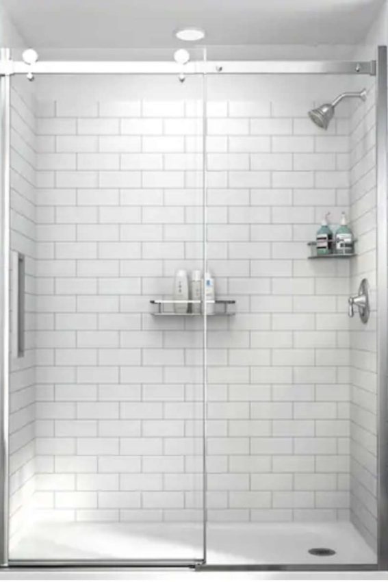 a shower with white subway tile and clear glass doors