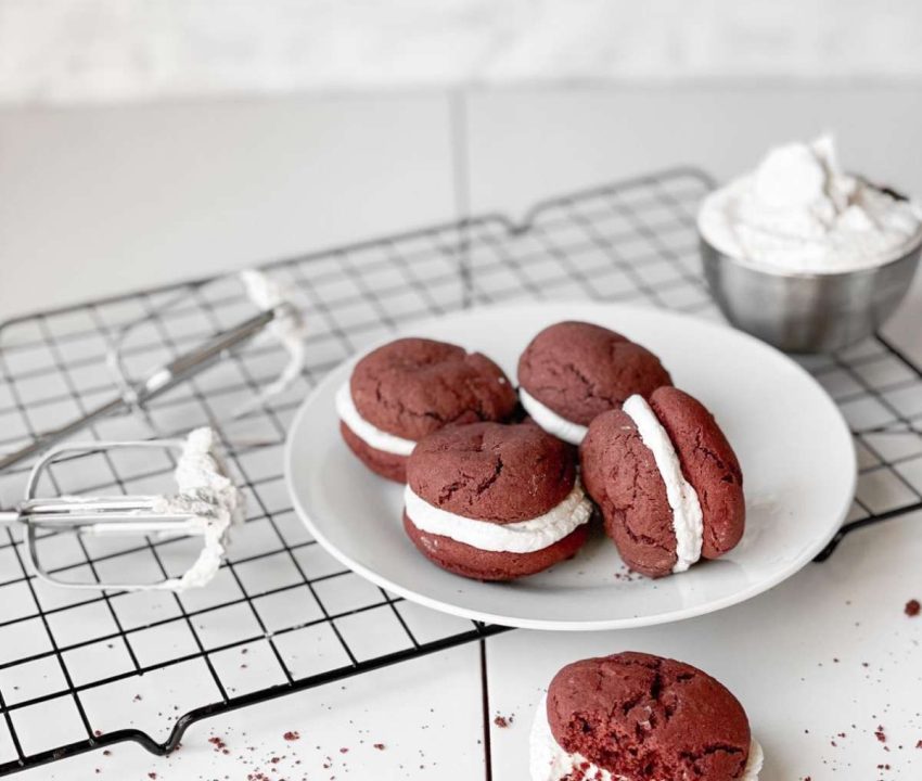 a plate of sandwich cookies with a bowl of frosting