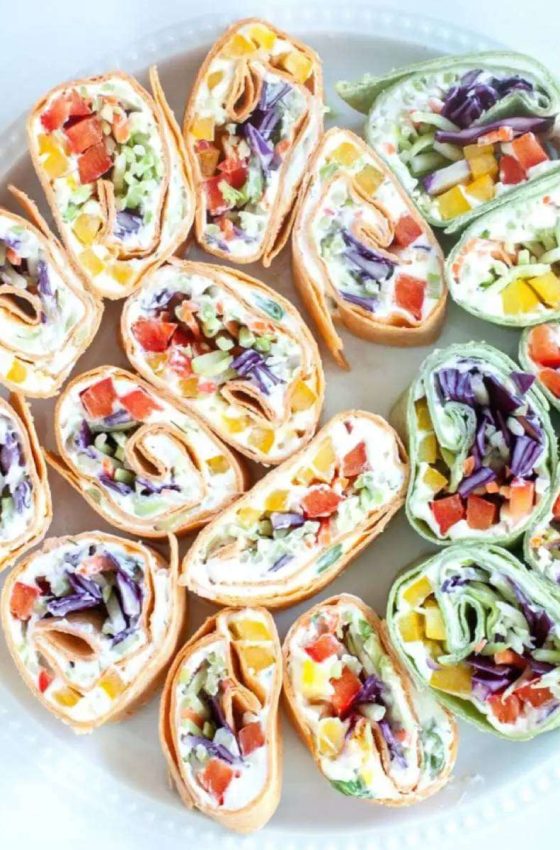 a round tray piled with vegetable pinwheels in different colored tortilla wraps
