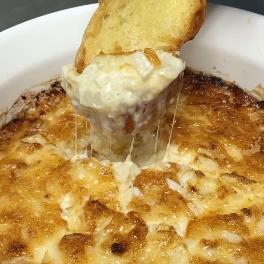 a baguette slice being pulled from the cheesy onion dip