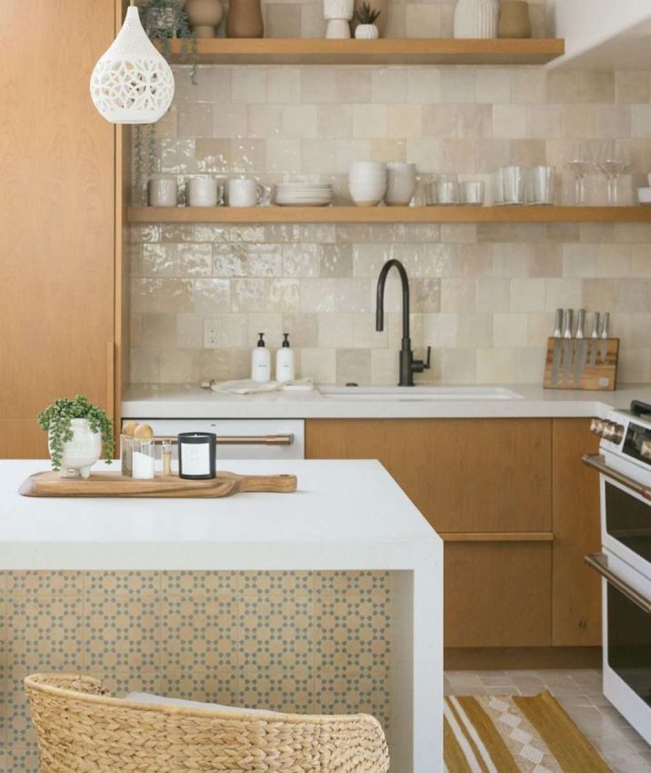 Light wood cabinetry & shelving, stone flooring in French pattern, 5" variegated cream zellige tile backsplash, white quartz countertops and waterfall on island, Moroccan style tile on back of island, woven seagrass counter stools, styled with plants, pottery and wood