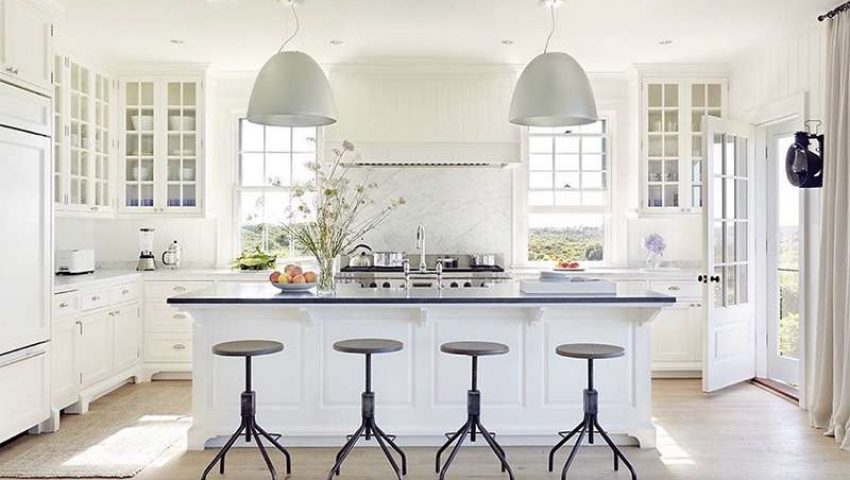 White kitchen with marble slab backsplash and oversized silver pendants
