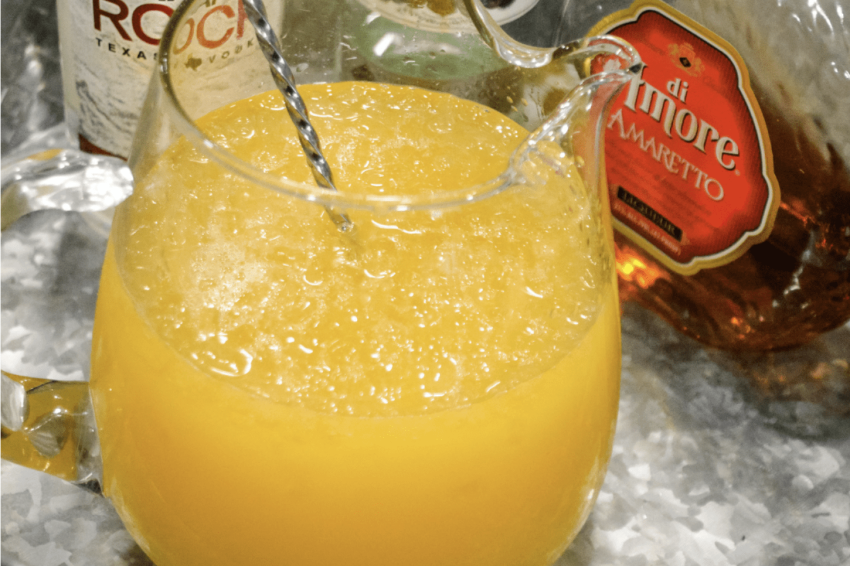 a pitcher of ice and alcohol with orange and pineapple juice