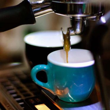 Espresso machine dripping the brew into a teal mug