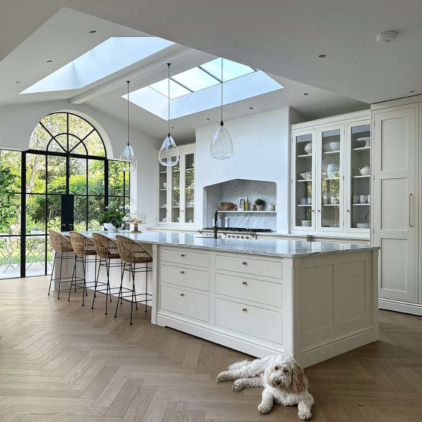 a white and marble kitchen with lots of light from 2 large skylights above the sink