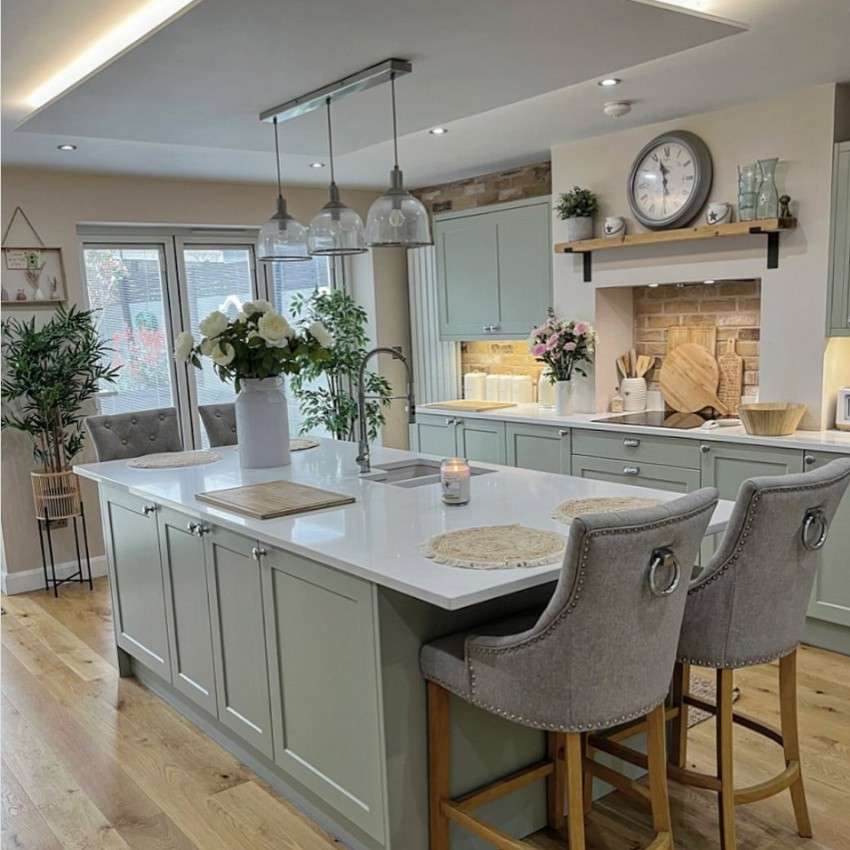 Farmhouse style kitchen with sage cabinetry and an island with a sink