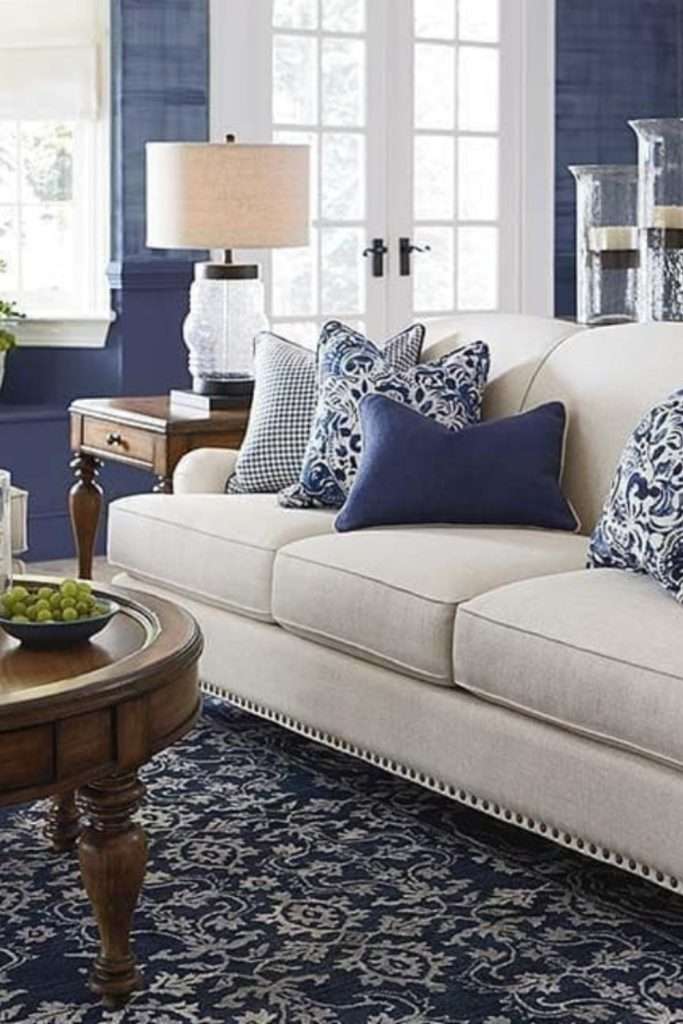 Coastal chic living room with dark navy accent wall, white sofa, and natural wood accents